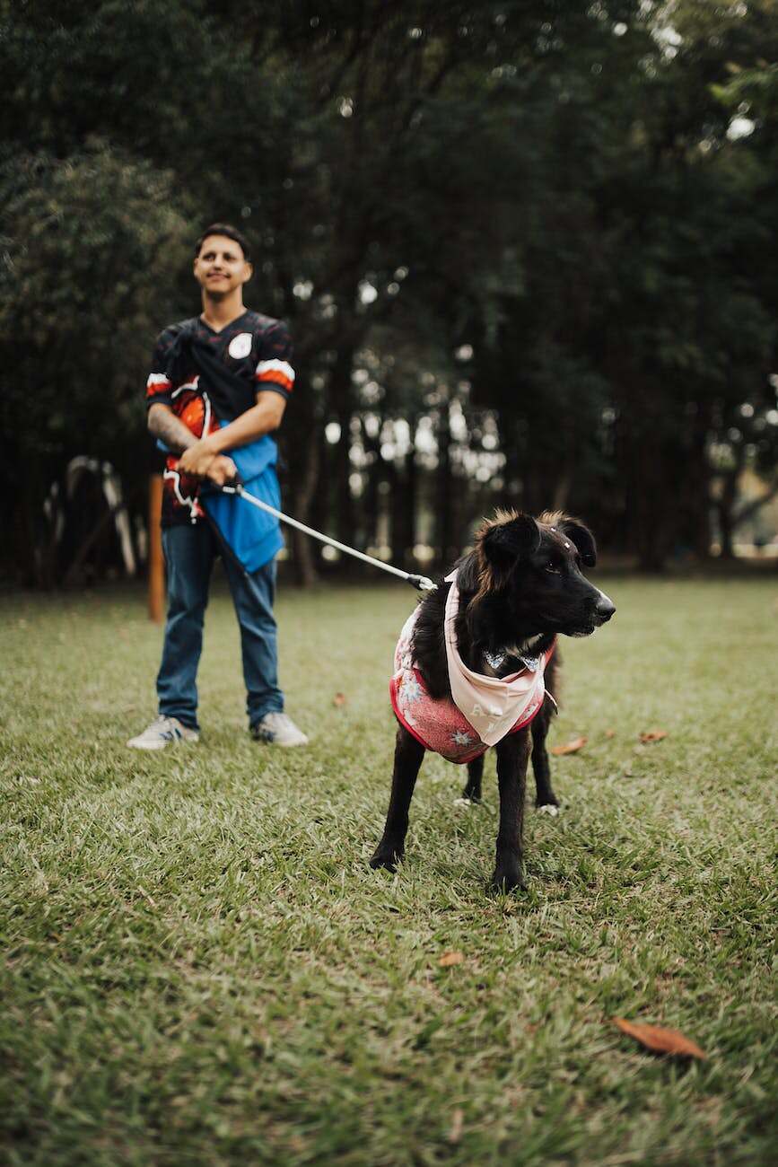 man holding his dog on a leash in a park